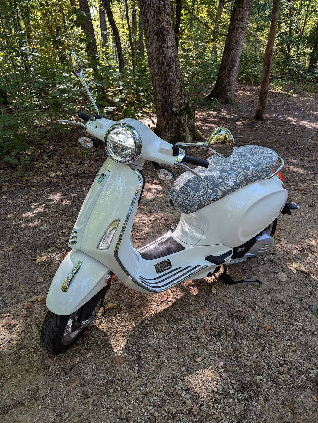 Stone Paisley seat cover fitted to a white Vespa Sprint or Primavera on a wooded trail, handmade by Cheeky Seats.