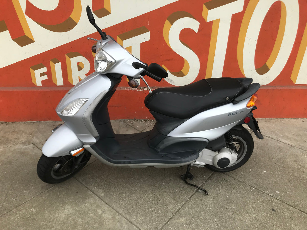 Silver Piaggio Fly 150 with a fitted matte black contoured seat cover, handmade by Cheeky Seats