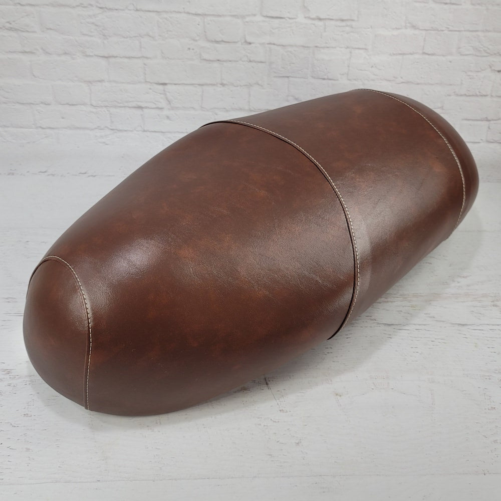Front three-quarter view of a distressed whiskey brown Lance Cali Classic and Havana Classic seat cover showing the center seam and tailored contours, handmade by Cheeky Seats