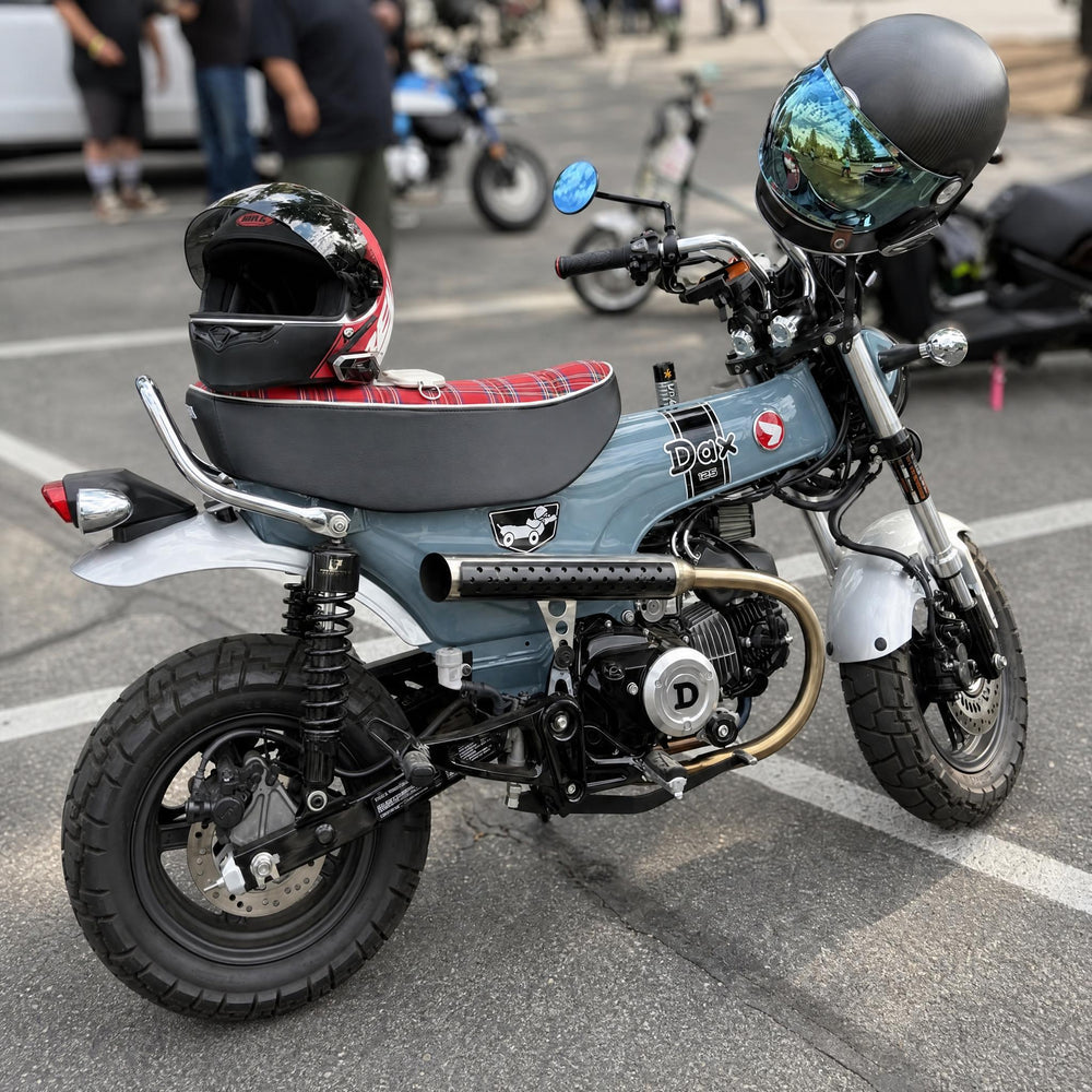 Pearl Gray Honda DAX 125 at a mini moto event with a red tartan plaid seat cover, white piping, handmade by Cheeky Seats