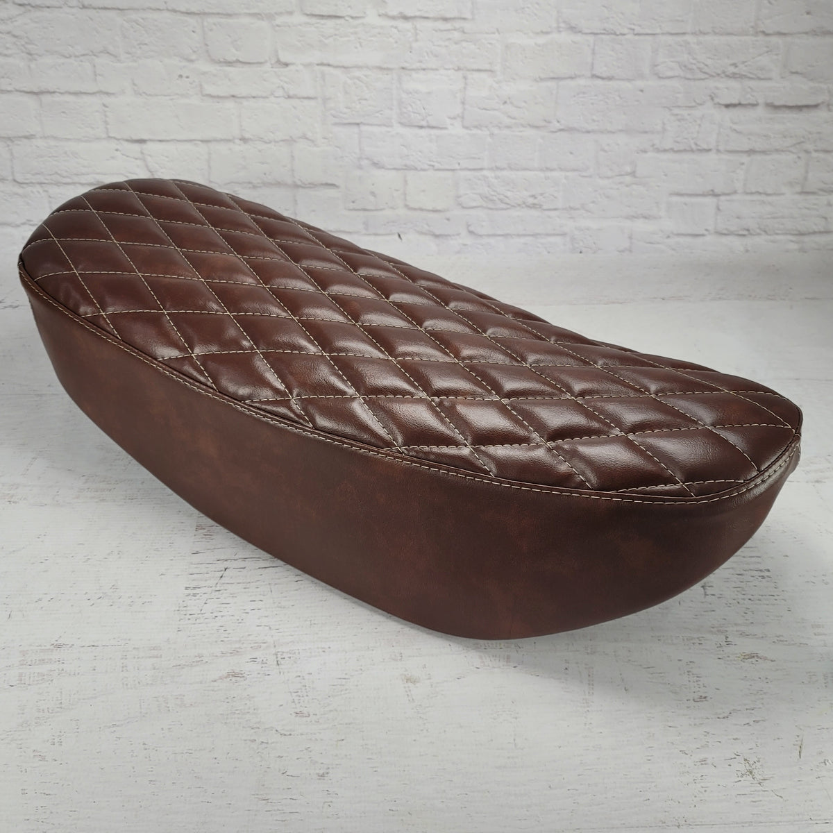 Low side view of a whiskey brown Honda DAX 125 cover with padded diamond sttiched and cream stitching, handmade by Cheeky Seats