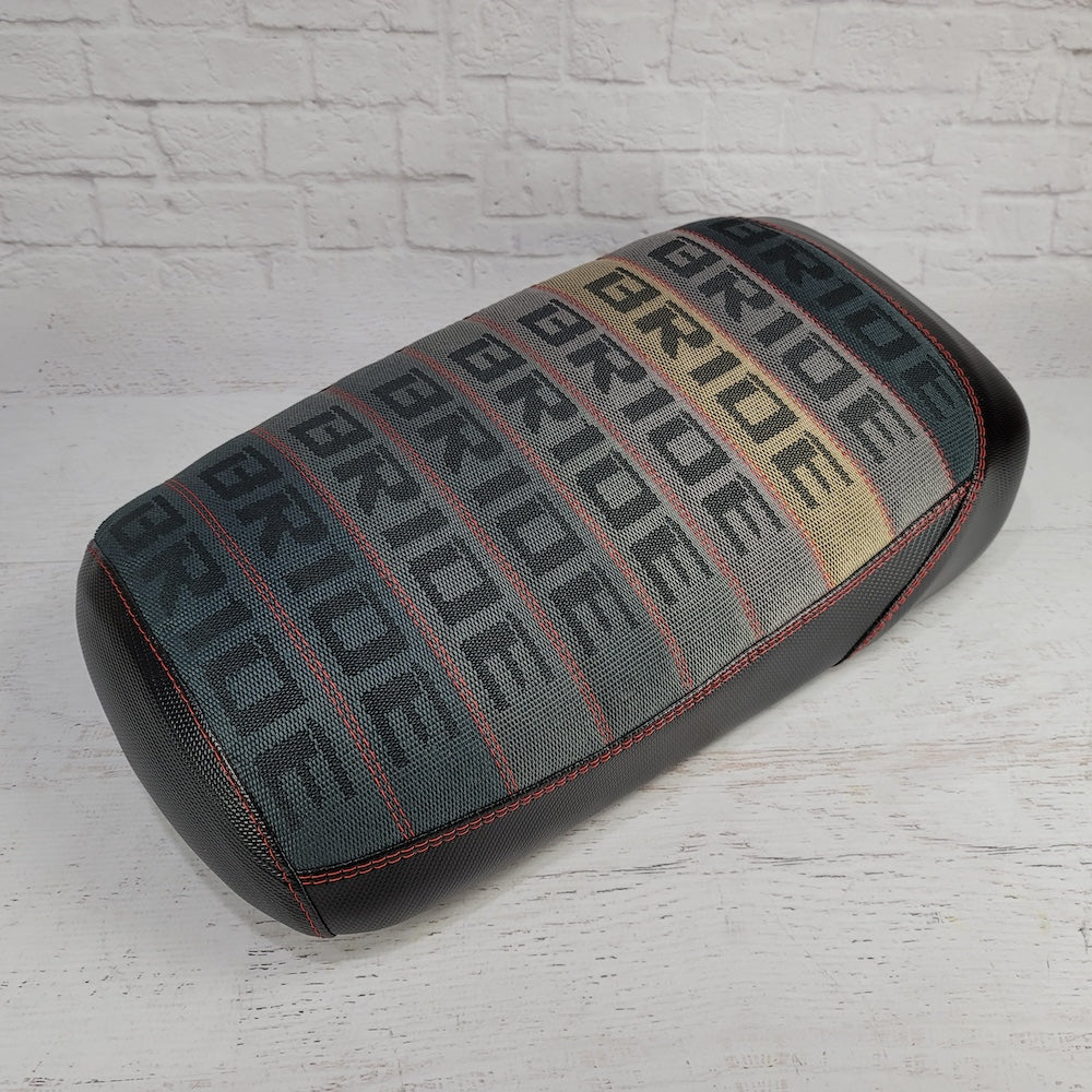 Maddog Gradient Bride fabric seat cover fading from dark gray to tan and cream with repeating BRIDE text, red stitching, and black side panels, handmade by Cheeky Seats