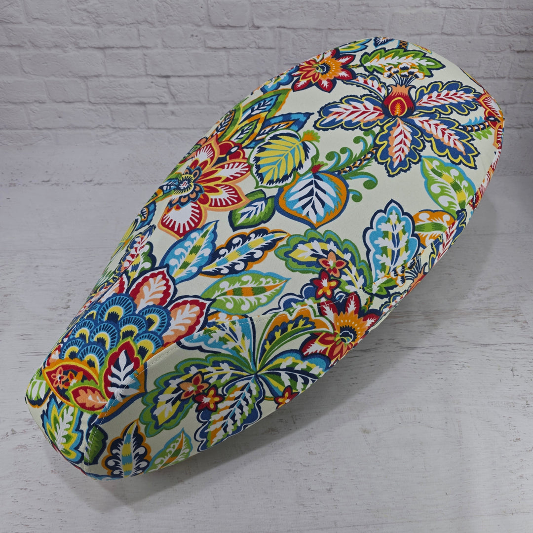 Colorful floral-patterned Vespa Seat cover on a white brick wall background Cheeky Seats 
