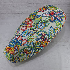 Colorful floral-patterned Vespa Seat cover on a white brick wall background Cheeky Seats 