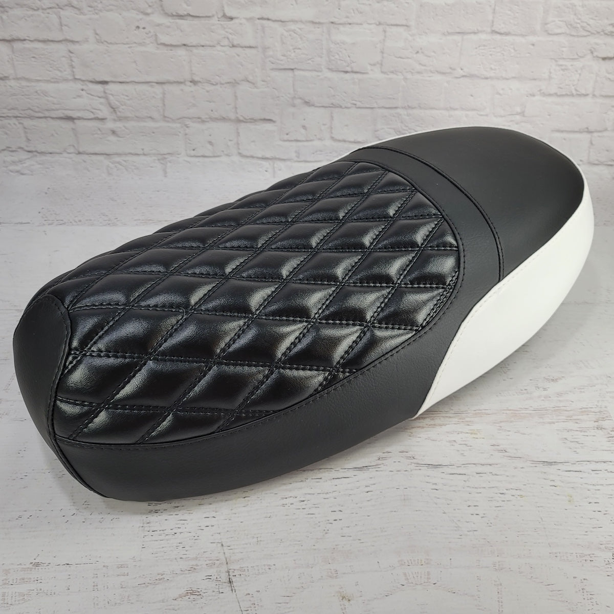 Rear three-quarter view of a black Yamaha Zuma II BWS 49/50 Prebug seat cover showing diamond stitching and white side panels, handmade by Cheeky Seats