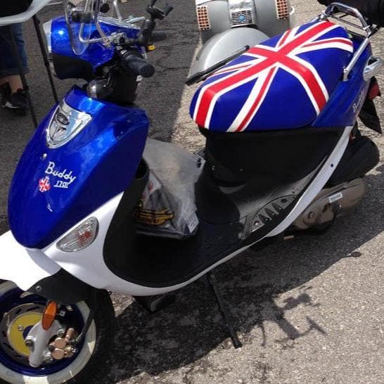 Blue-and-white Genuine Buddy 125 with a Union Jack Cheeky Seats cover, front-left view