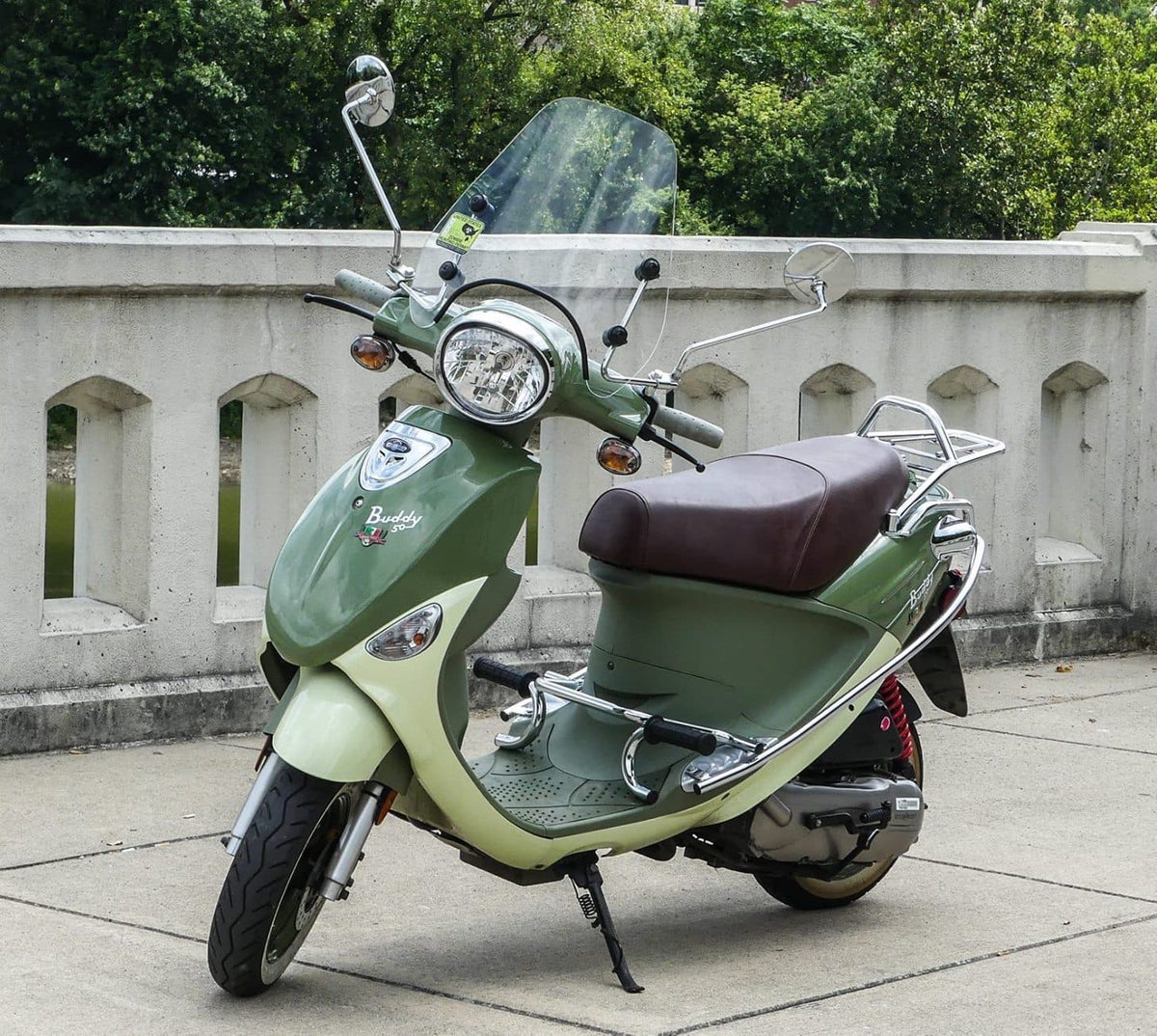 Whiskey-brown Cheeky Seats cover installed on a green Genuine Buddy 50 with windshield and racks