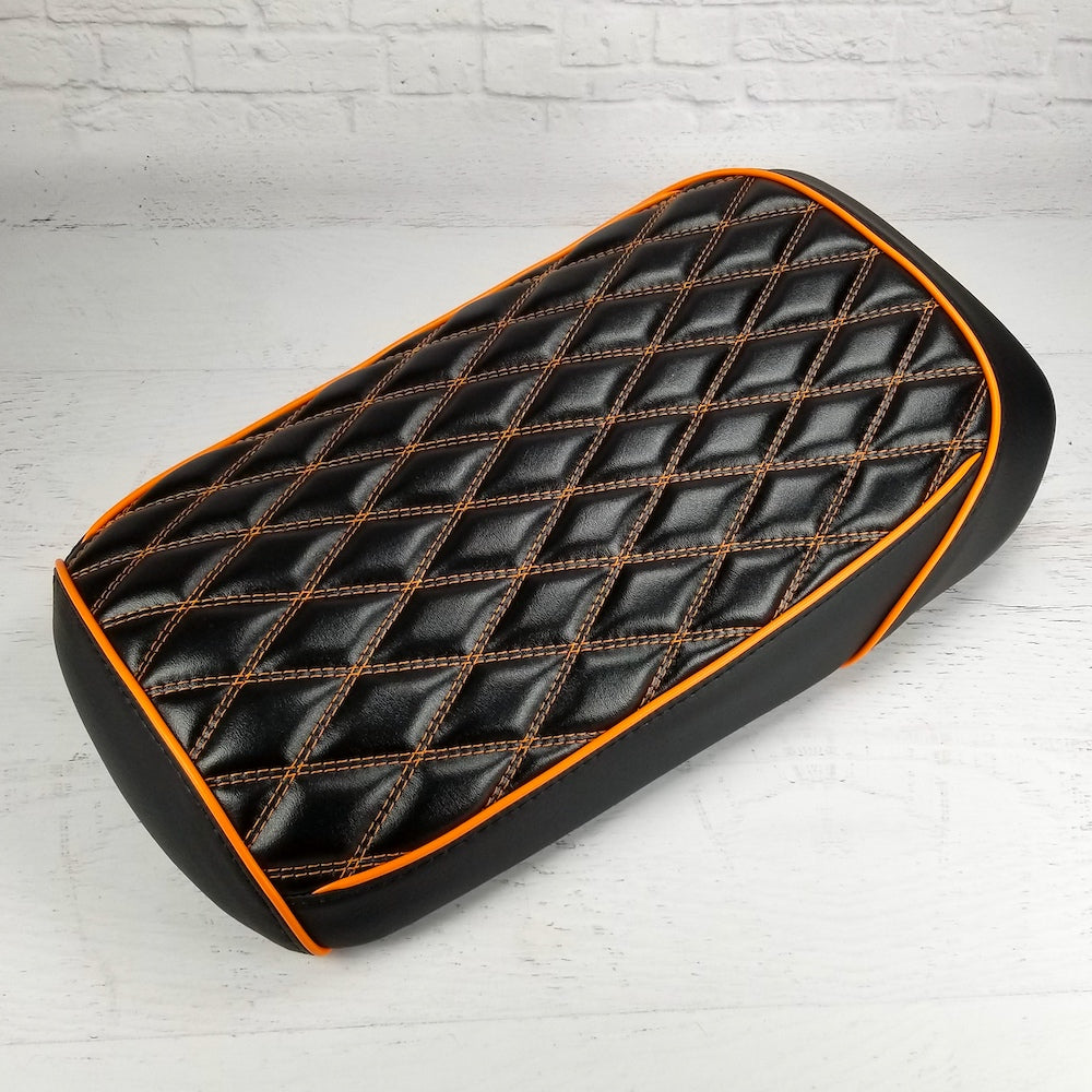 Black diamond-stitched Maddog seat cover with orange contrast stitching and orange piping, handmade by Cheeky Seats