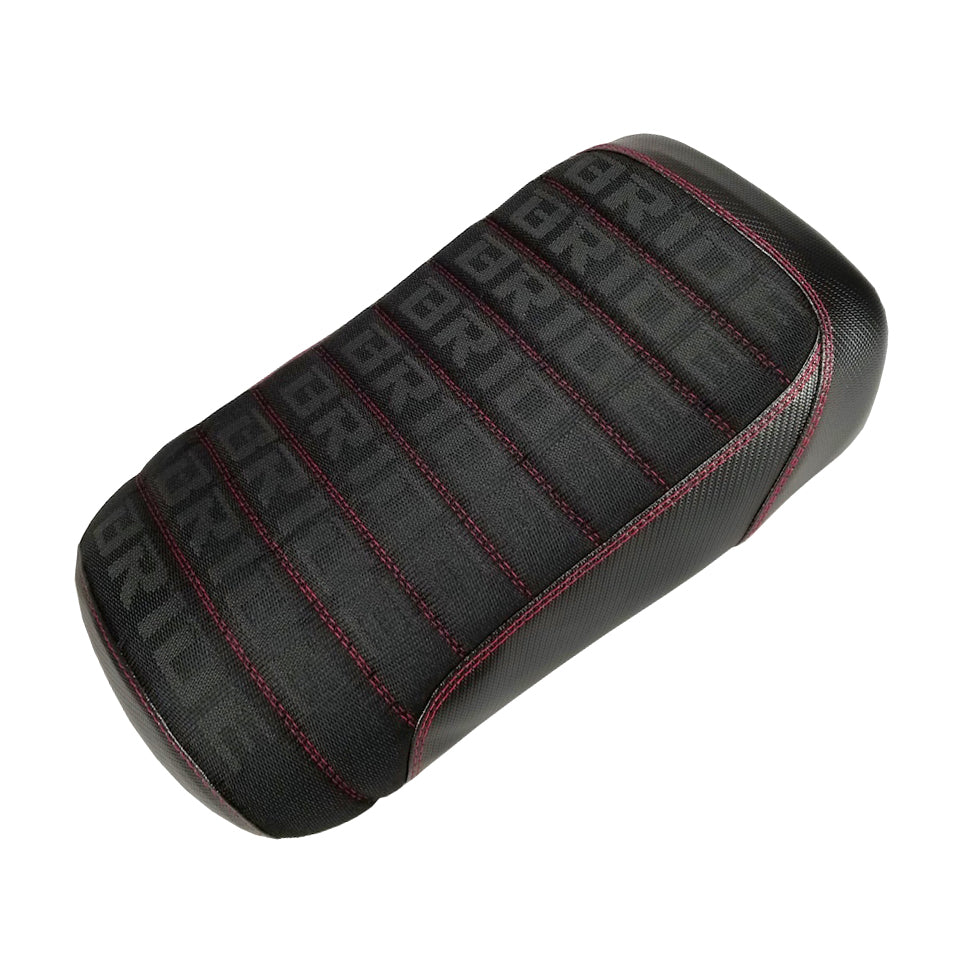 Black Bride fabric seat cover with repeating BRIDE text pattern, red contrast stitching, and padded tuck-and-roll pleats, handmade by Cheeky Seats